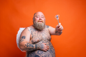 Fat happy man with beard ,tattoos and wings acts like an magic fairy