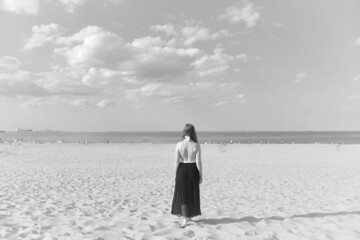 Stojąca tyłem kobieta na plaży  - obrazy, fototapety, plakaty