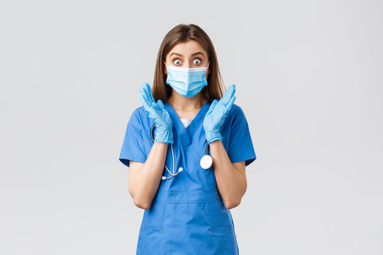 Covid-19, Preventing Virus, Health, Healthcare Workers And Quarantine Concept. Surprised And Shocked Female Nurse In Blue Scrubs And Medical Mask, Gasping Look Amazed Camera