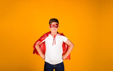 Fototapeta na wymiar a boy in a hero costume stands on a yellow background with a place for text