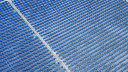 Background of solar panels array as seen from above the modern static solar power station. Green...