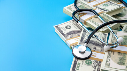 Profit driven hospital, premium medical insurance payment and high doctor bills expense concept with stethoscope, stacks of dollars and no people isolated on blue background with copy space - Powered by Adobe