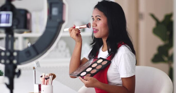 young asian woman streaming a beauty vlog from home, online content creator applying a makeup on, video tutorial
