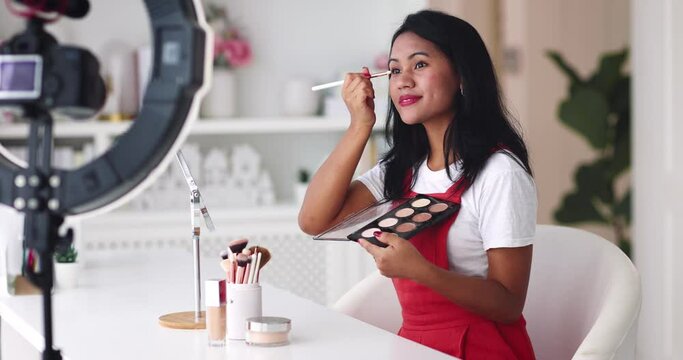 young asian woman streaming a beauty vlog from home, online content creator applying a makeup on, video tutorial