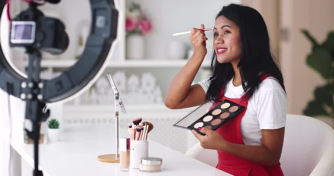 young asian woman streaming a beauty vlog from home, online content creator applying a makeup on, video tutorial