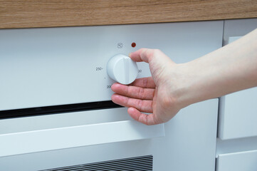 Switch for the built-in cooker. Caucasian woman hand switches regulator.
