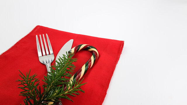 cutlery fork and knife on red napkins are isolated on a white background. a fir twig decorates the image. background for christmas cards. copy space