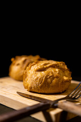 latin american stuffed potato, bolon. vertical photo with cutlery on wooden board. copy space