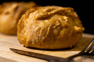 close up of latin american crispy stuffed potato, bolon. with cutlery on wooden board.