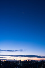 兵庫県神戸市東灘区の高層マンションの上層階からの夜明け。大阪生駒山から太陽が昇り、あたりはオレンジ色に染まり、ビル群がシルエットで浮かぶ。