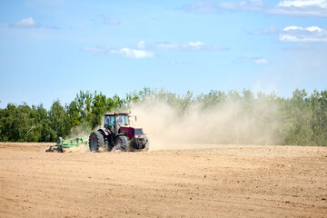 Tractor is plowing field with harrow. Typical agricultural scene tractor cultivation in field in...