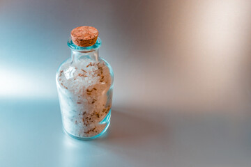 A large closed glass container with sea white salt stands against a light kitchen background.