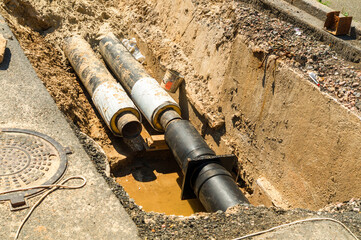 Water pipes in ground pit trench ditch during plumbing under construction repairing. Repair of a...