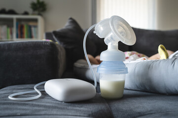 Electric Breast Pump Breastfeeding Machine and bottle with milk on bed