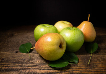 Pears and apples lying on a wooden table.Juicy bright fruits on a dark background.