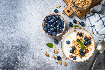 Yogurt with granola and fresh berries at stone table. Top view with copy space. Healthy food, snack or breakfast.