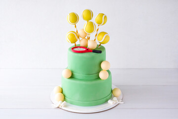 Green two-tiered tennis birthday cake decorated with yellow balls and racket