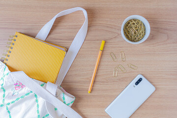 Neutral fashion composition with women's accessories and stationary on wooden table. Minimal lifestyle concept.