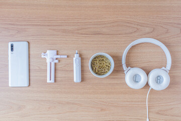 Workspace with headphone, paper cutter, eletric eraser, paper clips and smartphone on wooden background. Flat lay, top view. Minimalist concept.