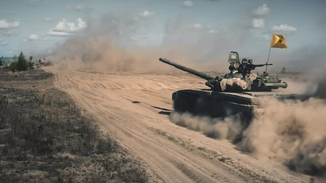 Strategic military training. Tank driving along sandy road close up. Dust from combat vehicle. Army maneuvers. Brown field with dry grass, blue sky. Country aggression. War. Tracking slow motion shot