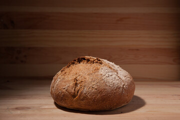Handmade fresh wheat bread on wooden background in the contrast light. horizontal frame side view with space area for text or design