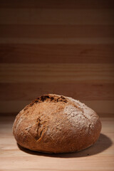 Handmade fresh wheat bread on wooden background in the contrast light. vertical frame side view with space area for text or design
