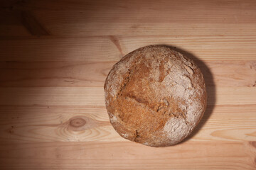 Handmade fresh wheat bread on wooden background in the contrast light. horizontal frame top view with space area for text or design