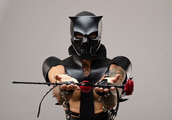 a man in bdsm wearing a skull demon mask with a whip, dressed in a leather raincoat with leather...