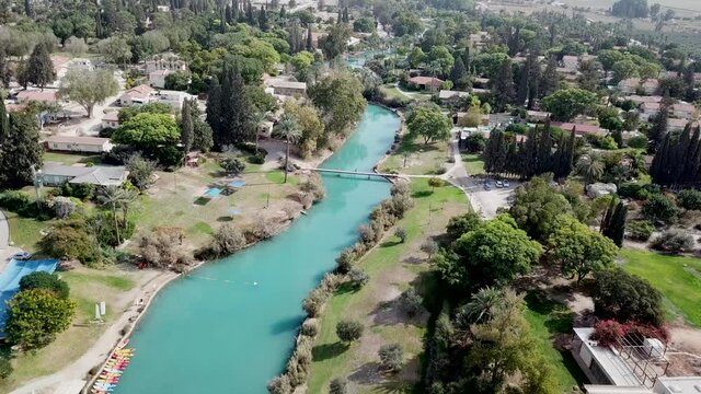 Aerial view flyover kibbutz Nir David, North of Israel. A view of farmland close to Beit shean valley with river channel dividing east and west side and Small Town With Red rooftops.