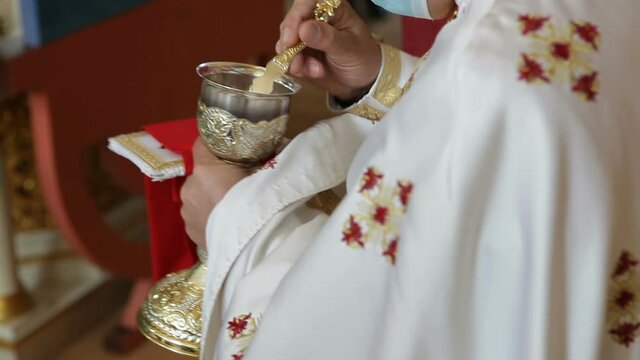 Communion in the church. The priest gives the parishioners bread and wine from a bowl.