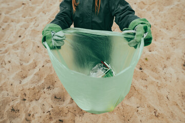 Kid picking up plastic garbage on the sand beach