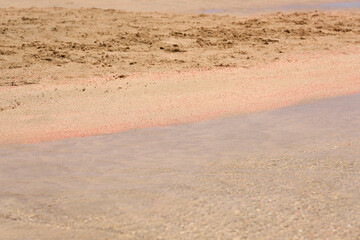 Clear waves and colorful sand on tropical sandy beach in Crete Greece.