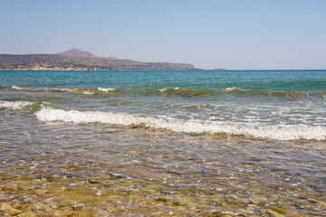 Waves with foam on Aegean sea coast in Crete Greece.