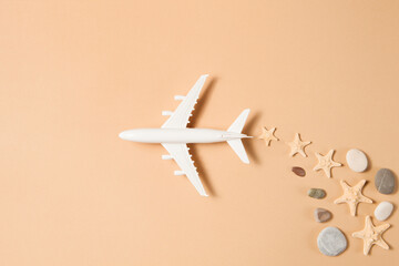 Flat lay design of travel concept with plane and trail made from starfishes and sea pebbles on...