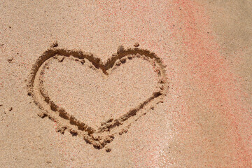 The heart is painted on the colored sand on a tropical beach.