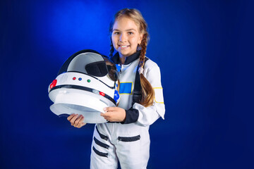 Teenager girl wearing astronaut costume and helmet standing on dark blue background © lithiumphoto