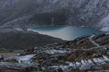 Hombre caminando en montaña junto a laguna