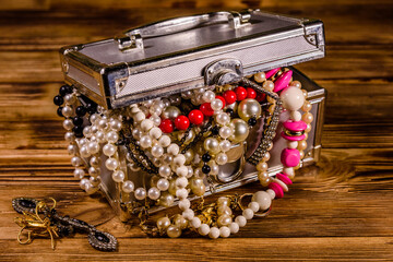 Aluminium case full of different jewelry on wooden table