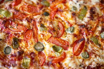 Delicious pizza topping background texture with tomatoes, paprika, cucumbers, salami and melted mozzarella cheese, viewed from above. Top down view.
