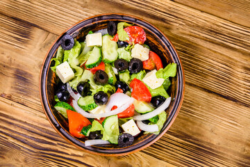 Ceramic plate with greek salad on wooden table. Top view