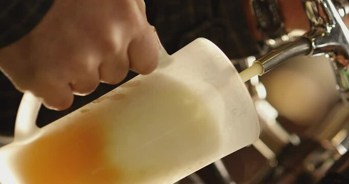 Pouring cold beer into glass. Bartender pouring craft beer in the bar. The hand of a master brewer pour from keg a light draft beer foam . Stout, Light, Unfiltered beer, ready to drink . Slow motion .
