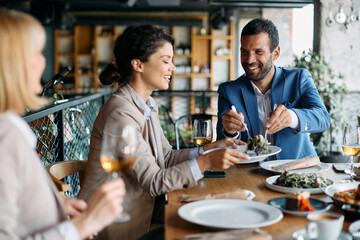 Group of happy business colleagues eat during lunch at restaurant.