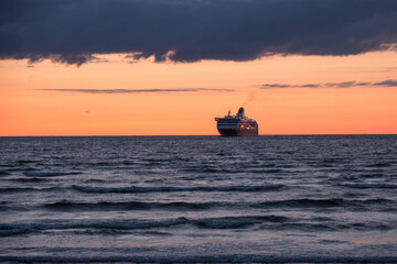 Cruise ship sailing at the horizon on the Baltic Sea after sunset, beautiful dramatic colors