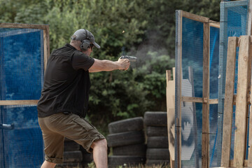 Man in tactical clothes shooting from a pistol, reloading the gun and aiming at the target in the...