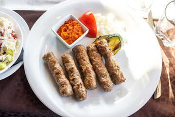 Grilled meat, cevapcici, served with sauce and onions. Traditional Balkan, Turkish food. Also known as Turkish kofta