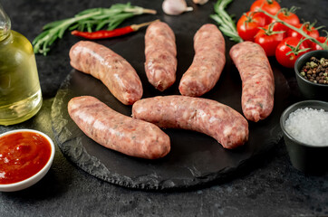 raw sausages for grilling on a stone background