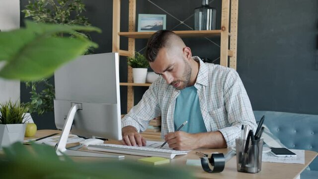 Ambitious freelance architect is working with computer then looking at construction plan on paper concentrated on work at home. People and remote job concept.