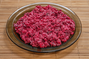 vegetarian vegetable salad with beets on a glass plate on bamboo straw surface, vegan lifestyle concept