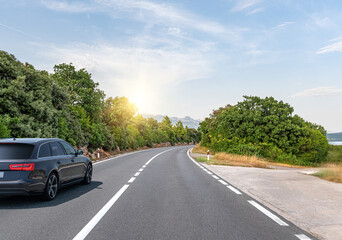 Fototapeta premium Black car on a scenic road. Car on the road surrounded by a magnificent natural landscape.