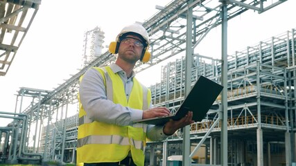 Refinery worker with a laptop on the plant premises